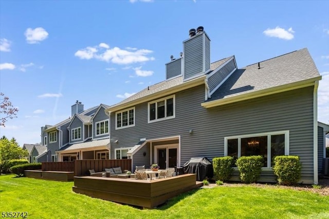 back of property with a chimney, an outdoor living space, a deck, and a yard