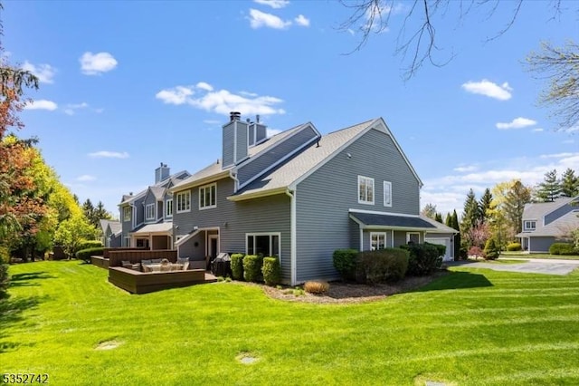 back of property featuring a lawn, a chimney, an outdoor hangout area, and a garage