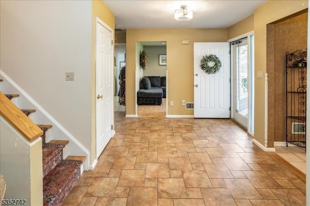 entrance foyer with baseboards, stairway, visible vents, and stone finish floor