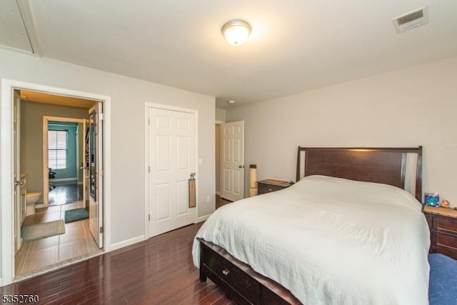 bedroom featuring attic access, visible vents, dark wood-style floors, and baseboards