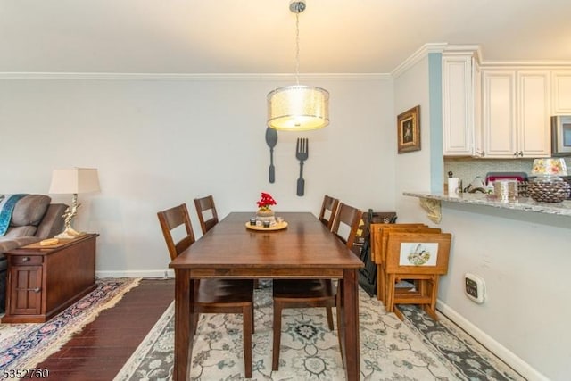 dining area featuring baseboards, ornamental molding, and light wood finished floors