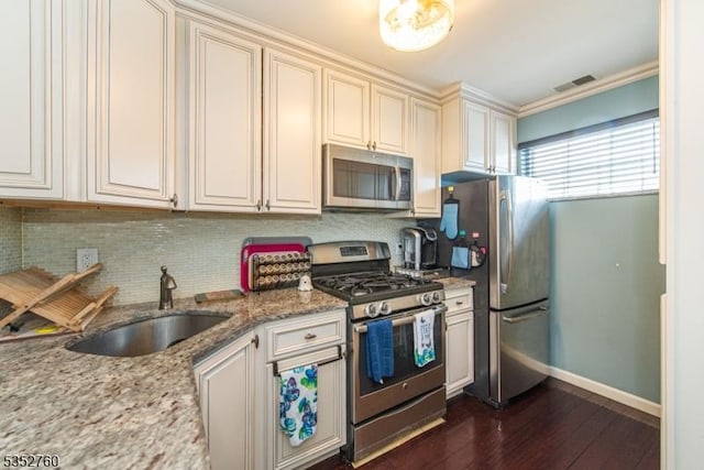 kitchen featuring decorative backsplash, a sink, appliances with stainless steel finishes, baseboards, and dark wood-type flooring