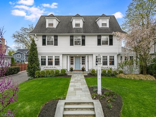 view of front of property with roof with shingles, fence, and a front yard
