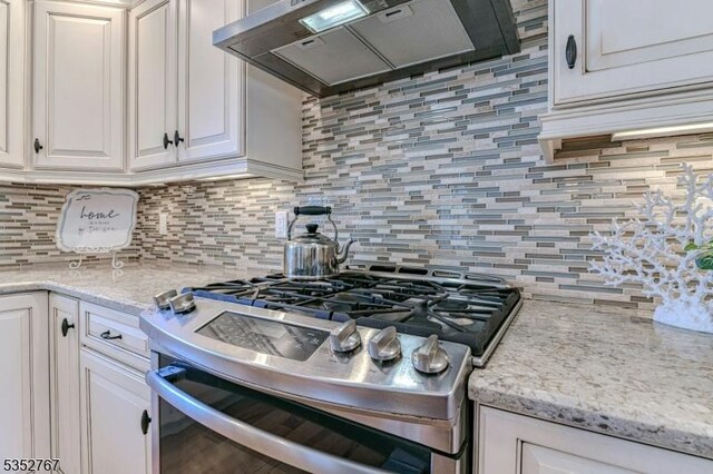 2210 Atlantic Ave, Long Beach Twp, NJ 08008 - kitchen with decorative backsplash, light stone countertops, white cabinets, stainless steel range with gas cooktop, and under cabinet range hood