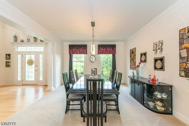 carpeted dining space with ornamental molding, ornate columns, and baseboards
