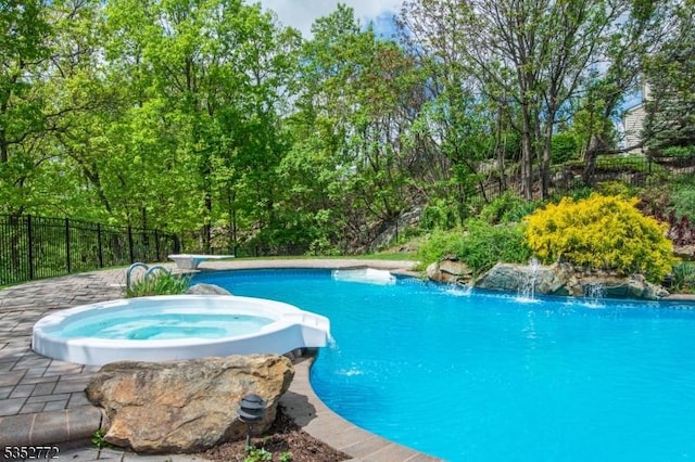view of swimming pool featuring fence and a pool with connected hot tub