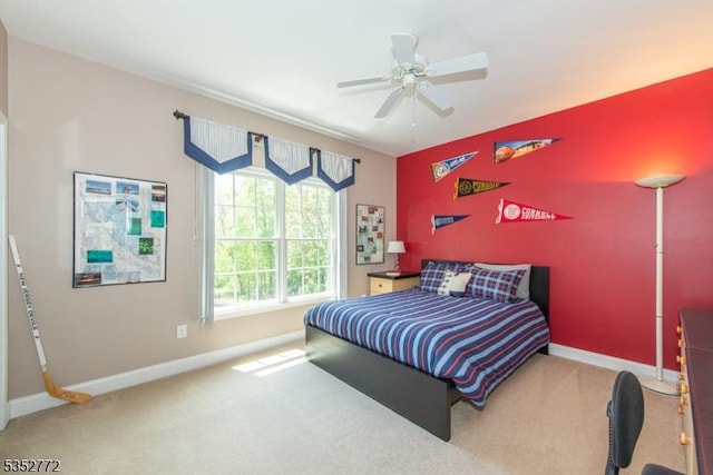 carpeted bedroom featuring baseboards, an accent wall, and a ceiling fan