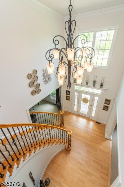 entryway featuring a chandelier, wood finished floors, stairs, ornamental molding, and a towering ceiling