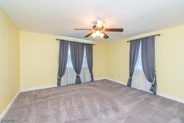 carpeted spare room featuring ceiling fan and baseboards