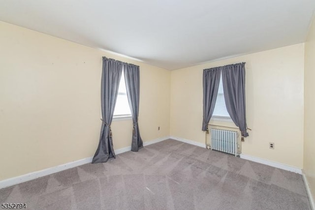 carpeted spare room featuring radiator heating unit and baseboards