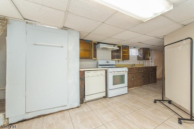 kitchen featuring a drop ceiling, under cabinet range hood, light countertops, light tile patterned floors, and white appliances