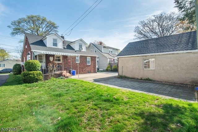 rear view of house with roof with shingles and a yard
