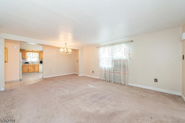 unfurnished living room with light carpet, baseboards, and a chandelier