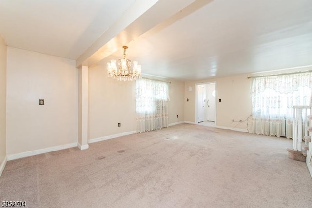 empty room featuring carpet floors, baseboards, and an inviting chandelier