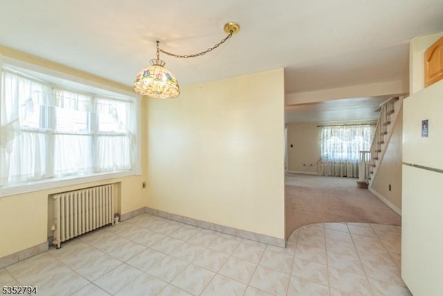 empty room featuring stairway, radiator, baseboards, and light tile patterned floors
