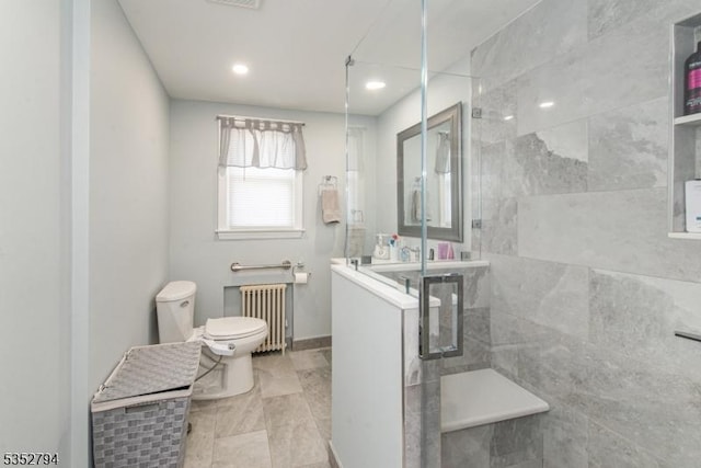 bathroom featuring baseboards, toilet, radiator heating unit, and tiled shower