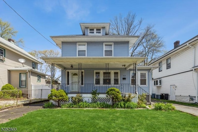 american foursquare style home with fence, a porch, a front lawn, and cooling unit