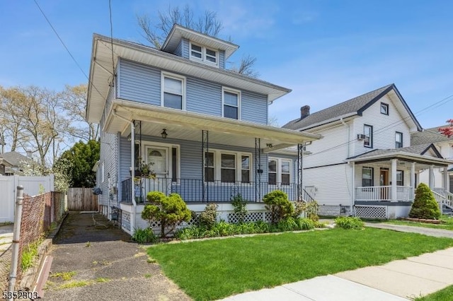 american foursquare style home with covered porch, fence, and a front yard
