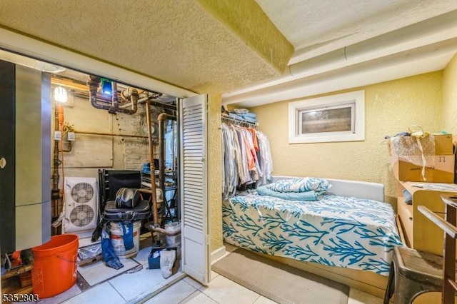 bedroom with a textured ceiling, a textured wall, and tile patterned flooring