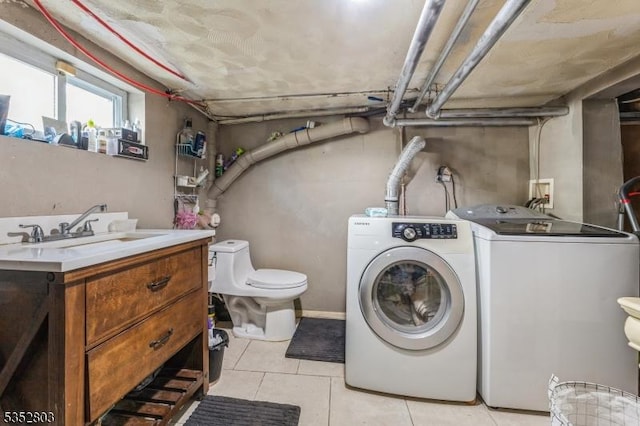 washroom featuring light tile patterned floors, separate washer and dryer, laundry area, and a sink