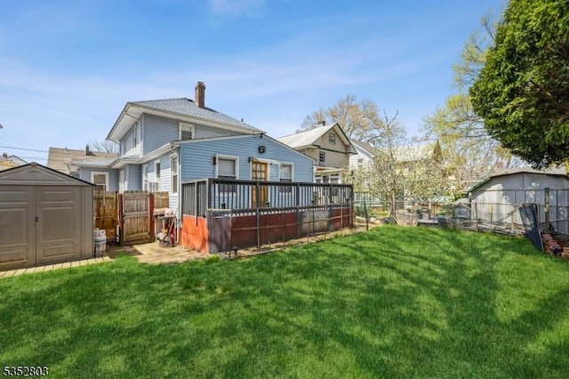 rear view of property with a storage shed, a lawn, a fenced backyard, and a chimney