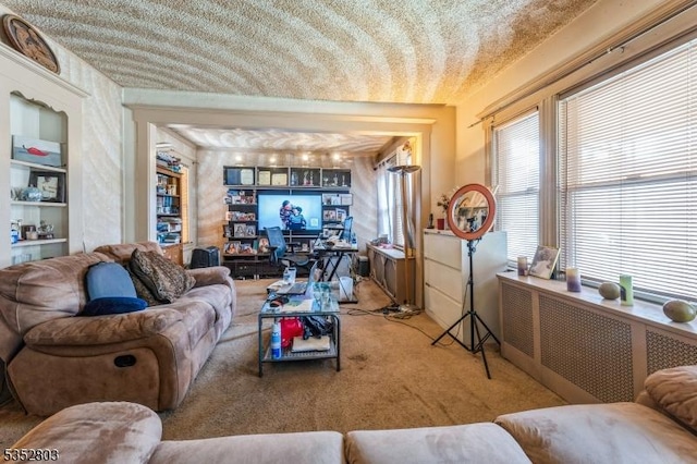 carpeted living room featuring built in shelves, a textured ceiling, and plenty of natural light