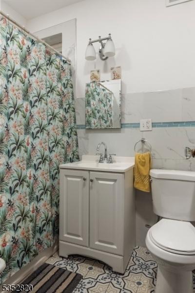 222 Van Buren St, Newark City, NJ 07105 - bathroom featuring vanity, toilet, tile walls, a shower with shower curtain, and tile patterned floors