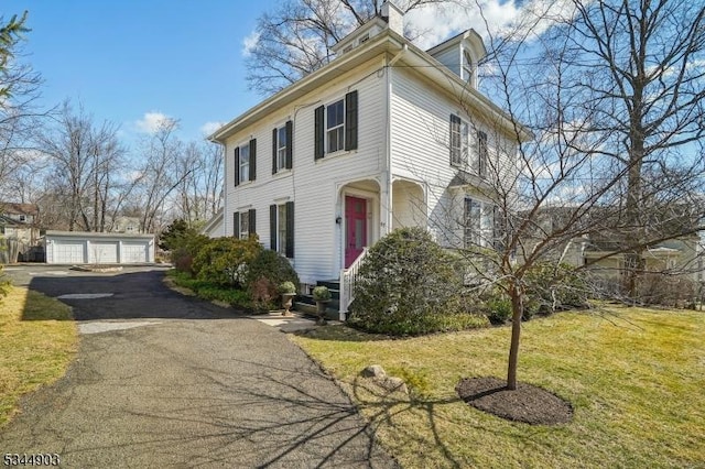 view of front of home with a front lawn, an outbuilding, a chimney, and a garage