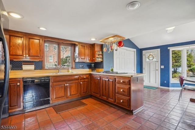kitchen featuring light countertops, dishwasher, vaulted ceiling, a sink, and a peninsula