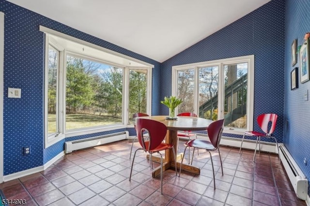 tiled dining space with a baseboard heating unit, wallpapered walls, vaulted ceiling, and a healthy amount of sunlight