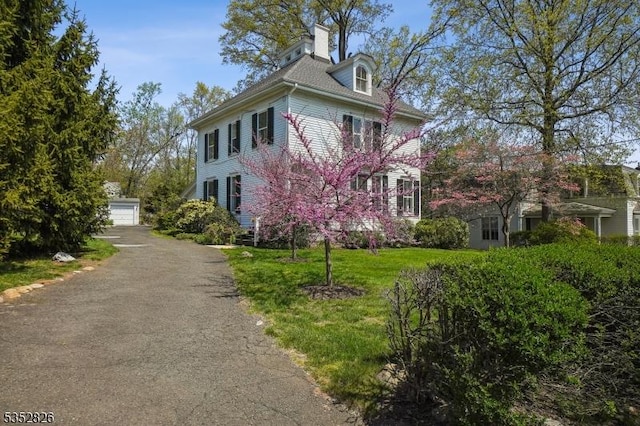 view of side of property featuring a detached garage and an outbuilding
