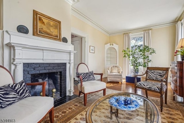 sitting room with wood finished floors, a brick fireplace, and ornamental molding