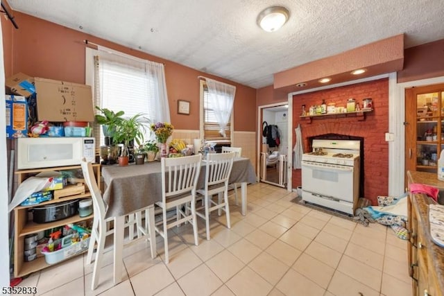 76 Kossuth St, Newark City, NJ 07105 - kitchen featuring white appliances, a textured ceiling, wainscoting, and light tile patterned floors