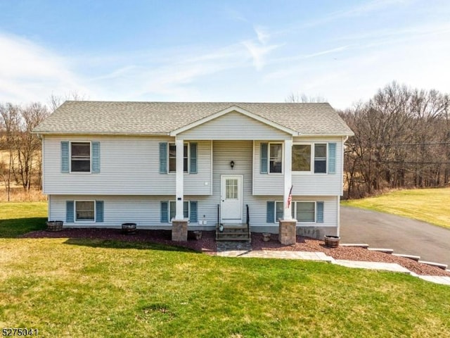 bi-level home with a shingled roof, a front lawn, and aphalt driveway