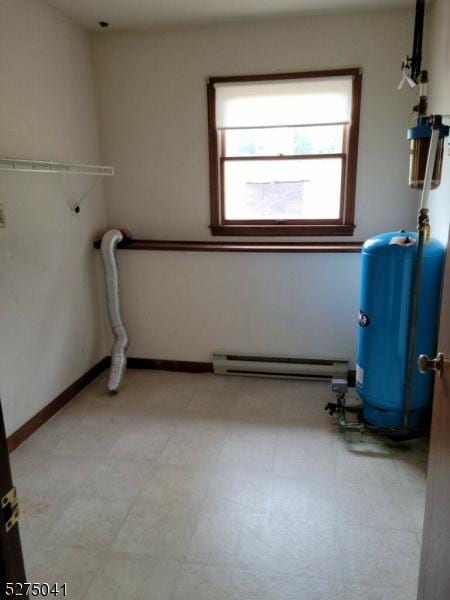 laundry room featuring a baseboard radiator, a wealth of natural light, tile patterned floors, and baseboards