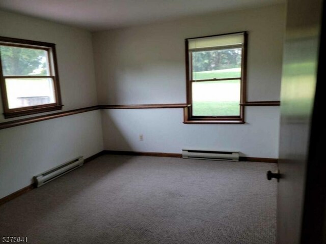 unfurnished room with a baseboard heating unit, carpet floors, and a healthy amount of sunlight