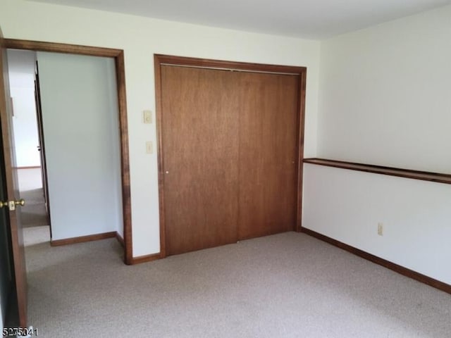 unfurnished bedroom featuring baseboards, carpet, and a closet
