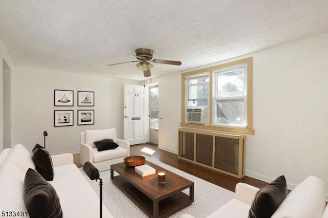living room featuring a ceiling fan, a textured ceiling, wood finished floors, baseboards, and radiator
