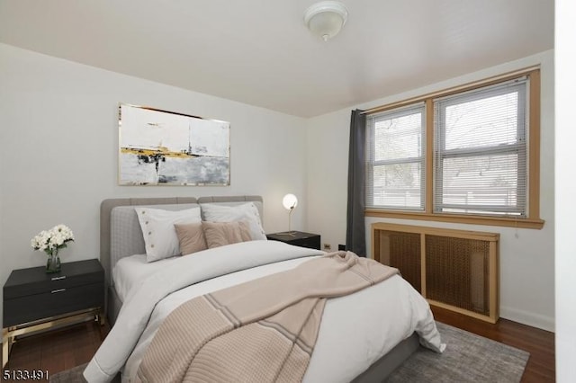 bedroom featuring wood finished floors, baseboards, and radiator heating unit