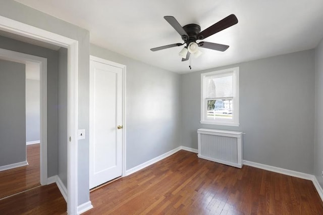 unfurnished bedroom featuring baseboards, radiator, and hardwood / wood-style flooring