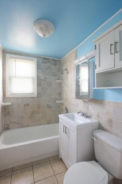 bathroom featuring tile patterned flooring, vanity, toilet, tile walls, and shower / bathing tub combination