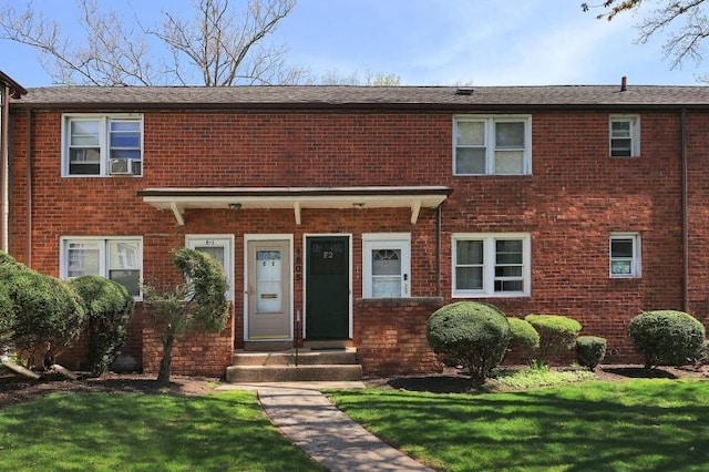 townhome / multi-family property featuring a front lawn and brick siding