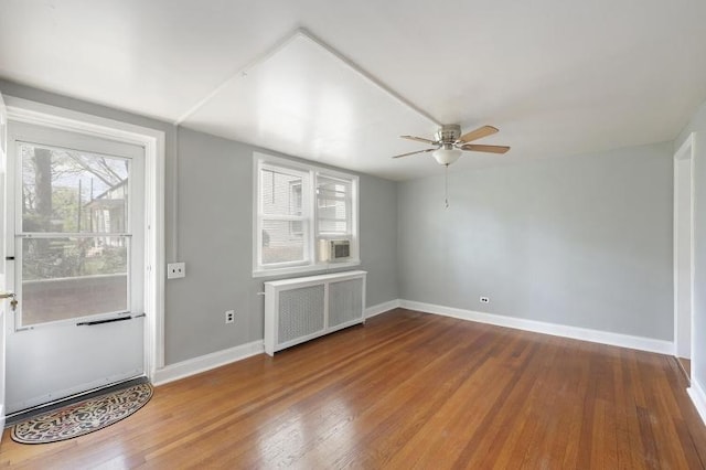 foyer entrance with radiator, ceiling fan, baseboards, and wood finished floors