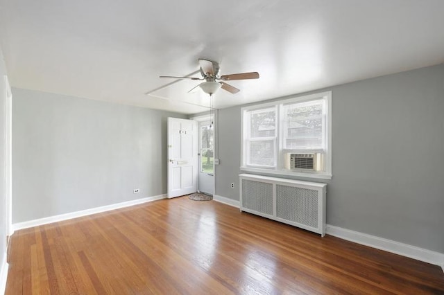 spare room with radiator heating unit, ceiling fan, plenty of natural light, and wood finished floors