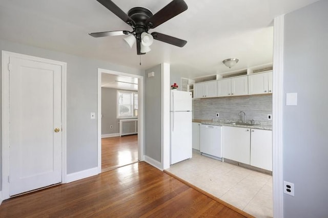 kitchen featuring white appliances, light countertops, white cabinets, tasteful backsplash, and a sink