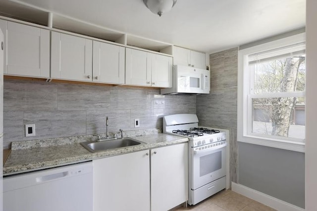 kitchen featuring white appliances, light tile patterned floors, white cabinets, a sink, and backsplash