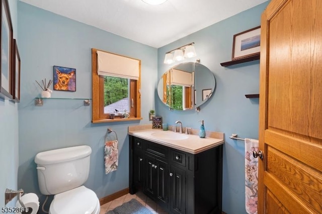 bathroom with toilet, tile patterned flooring, vanity, and baseboards