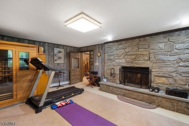 exercise room with carpet, a fireplace, wooden walls, and ornamental molding