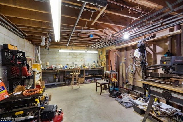 unfinished basement with a workshop area and concrete block wall