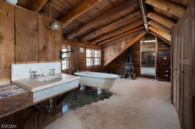 bathroom with wooden walls, a freestanding bath, a wood stove, wooden ceiling, and vaulted ceiling with beams
